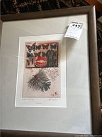 Framed numbered art print showing full lot with glass reflection and attached auction tag.