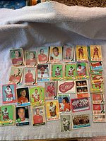 Photo of approximately 30 hockey cards spread out on a cloth surface, showing various Detroit Red Wings players from the 1969-1976 era.