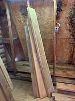 Full view of the stack of 2x8 rough sawn hardwood lumber boards leaning against wall