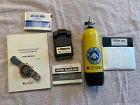 Photo of Citizen Hyper Aqualand watch and related accessories including manuals, communication unit, and diving tank model