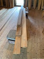 Four pine lumber boards arranged on a wood floor in a workshop. Visible are thick boards, rough cut, laid on sawhorses. Natural wood grain, knots, and some surface marks.