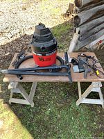 Full view of the Shop Vac with hose, wand attachments, and electrical cords on the table outdoors