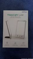 Box of Verilux HappyLight Luxe LED Light Therapy Lamp showing product image and branding.