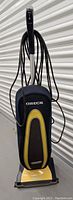 Front view of yellow and black Oreck XL upright vacuum cleaner with cloth bag and power cord wrapped around handle.