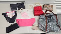 Overview shot showing all items in the lot: purses, tote bags, wallets, and packaged items.