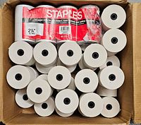 Top view of the lot showing 20 white paper rolls in a cardboard box, some in original packaging labeled Staples