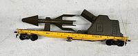 Side view of vintage metal Air Force missile train flatcar showing missile and cannon mounted on yellow flatcar.
