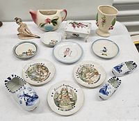 Image showing vintage decorative ceramic plates from United States Postal Service 'Colonial Craftsmen' series along with other decorative ceramic items including miniature shoes, a figurine, vase, and trinket box.