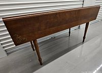 Side view of vintage solid wood table with legs and floral corner decoration
