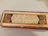 Close-up photo of one side of the original box showing text about learning to play the harmonica and M. Hohner Inc. New York City.