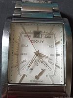 Close-up photo of the DKNY watch face showing date window, hour markers, and 24-hour subdial