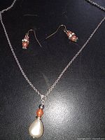 Photo of freshwater pearl necklace on silver chain with matching beaded earrings on black background.