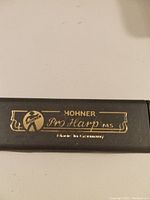 Close-up photo of black harmonica cover plate with gold lettering stating 'Hohner Pro Harp MS' and 'Made in Germany'