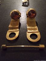 Gold tone men's mesh strap cuff links with brown gemstone-like centers and gold tone bar tie clip with screw ends.