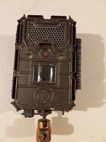 Front view of the Bushnell Trophy Cam Essential E3 trail camera mounted on a swivel mount, showing lens, sensors, and textured front design.