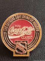 Close-up photo of the front face of the Coca-Cola NHL vintage enamel pin showing logos and text.