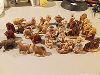 Photo showing 28 assorted vintage Wade figurines on display including various animals and human characters.