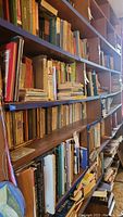Long view of bookshelf showing many hardcover and softcover books organized on wooden shelving.