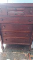 Full front view of an 8-drawer wooden chest showing wear, scratches, and a missing drawer handle.