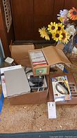 Photo of the entire lot showing boxes containing cassette tapes, the powered scissors packaging, and some electronic devices including the Nook tablet box.