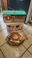 Full view of boxes and fish-shaped platter and plates on tile floor