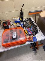 Full tabletop view showing Black & Decker drill, accessory case, miscellaneous hardware, power bars, and folding roller support.
