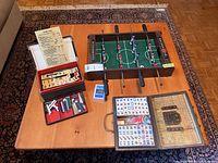 Overview of lot on wooden low table, showing mini foosball table, two Mahjong sets, playing cards and score card.