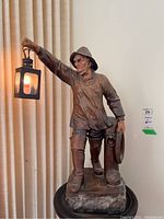 Full front view of ceramic fisherman statue lamp on base