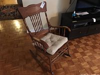 Full view of wooden rocking chair with cushion on seat showing shape and details