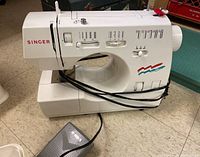Full side view of Singer sewing machine with control pedal laying on the floor.