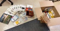 Overview of stamps, albums, viewer tools, and other stamp collection materials spread on floor and in a box.