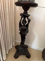 Full view of carved wood stand showing base, figurine support, and top platform