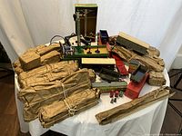 Overview of multiple paper-wrapped track packs, transformer, cars, accessories on table