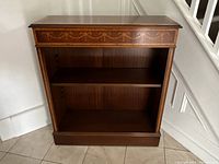 Front view showing open‐front bookshelf with decorative inlay