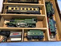 Original cardboard box interior divided into compartments holding two Pullman coaches, Flying Scotsman locomotive #4472, tank engine, tender and brake van