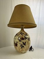 Full view of mid-century ceramic lamp with beige fabric shade showing overall shape and size.