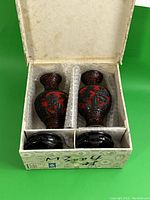Pair of black and cinnabar lacquer vases with fitted wooden stands in original box. Box shows wear and age, foam padding present.