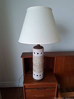 Full view of one lamp on wooden cabinet showing shade and base