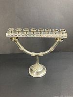 Front view of sterling silver menorah showing eight candle cups and filigree details