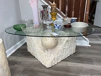 Full top and side view of coffee table showing glass top and various items placed on it.