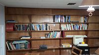 Bookshelves with a variety of books mostly hardcover and paperback, showing signs of age and use