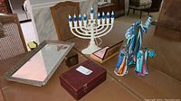 Overview of lot items on a table including jewelry boxes, mirrored tray, electric menorah, and religious figurines