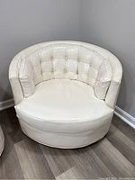 Front view of a white swivel barrel chair with tufted back and cushioned seating shows some wear and staining, cushion taped.