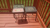 Three outdoor side tables on reddish wood deck, two metal frame with glass tops, one metal with tile top. Showing dirt and residue.