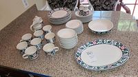 View of full dish set showing coffee cups, bowls, plates, platters, sugar bowl, and salt & pepper shakers on countertop.