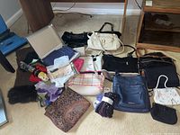 Overview of the lot including various purses, scarves, socks laid out on floor.