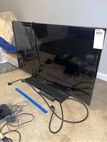 Front view of Samsung 40-inch LED TV with visible power cable and remote on the carpeted floor.