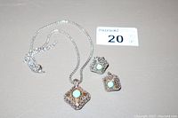 Set of 18kt gold necklace and earrings with turquoise beads and clear stones, showing the necklace chain and pendant along with the earrings.