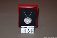Heart-shaped crystal pendant necklace displayed inside red box with black velvet interior, pendant front view.