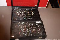 Top-down image of two open black display cases containing colorful 14 gauge tongue and belly button rings arranged on black fabric with metal loops.
